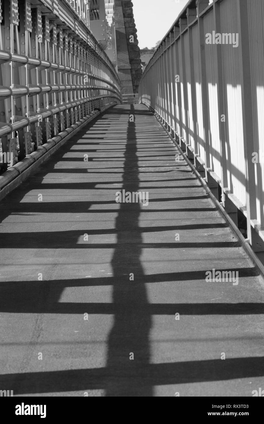 Walkway over the Menai Suspension bridge with strong shadows from the sun. Stock Photo