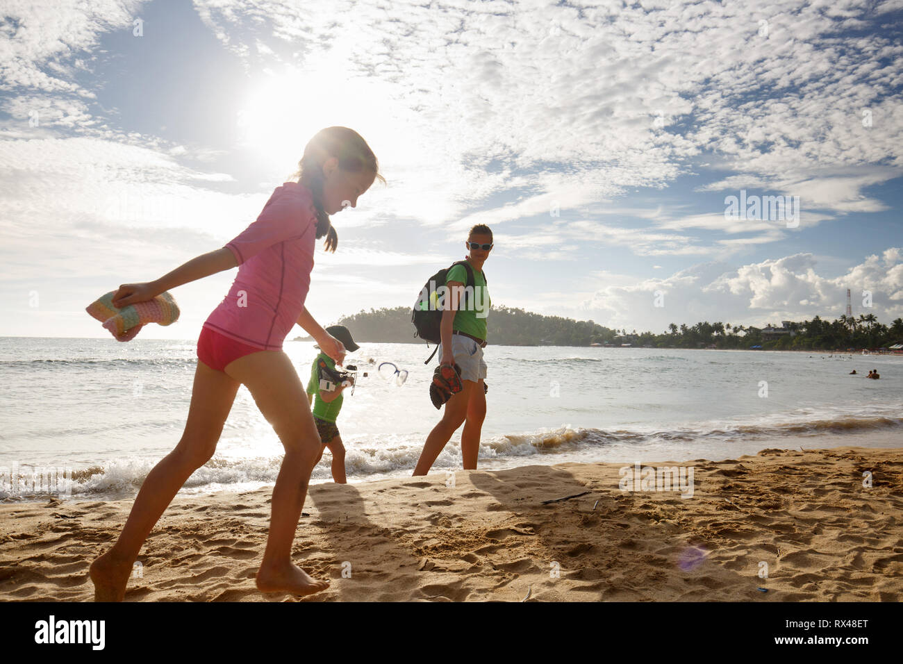 Mother with children enjoying a tropical beach hike. Travelling with children, beach hopping, family time, active lifestyle, beach fun concept. Stock Photo