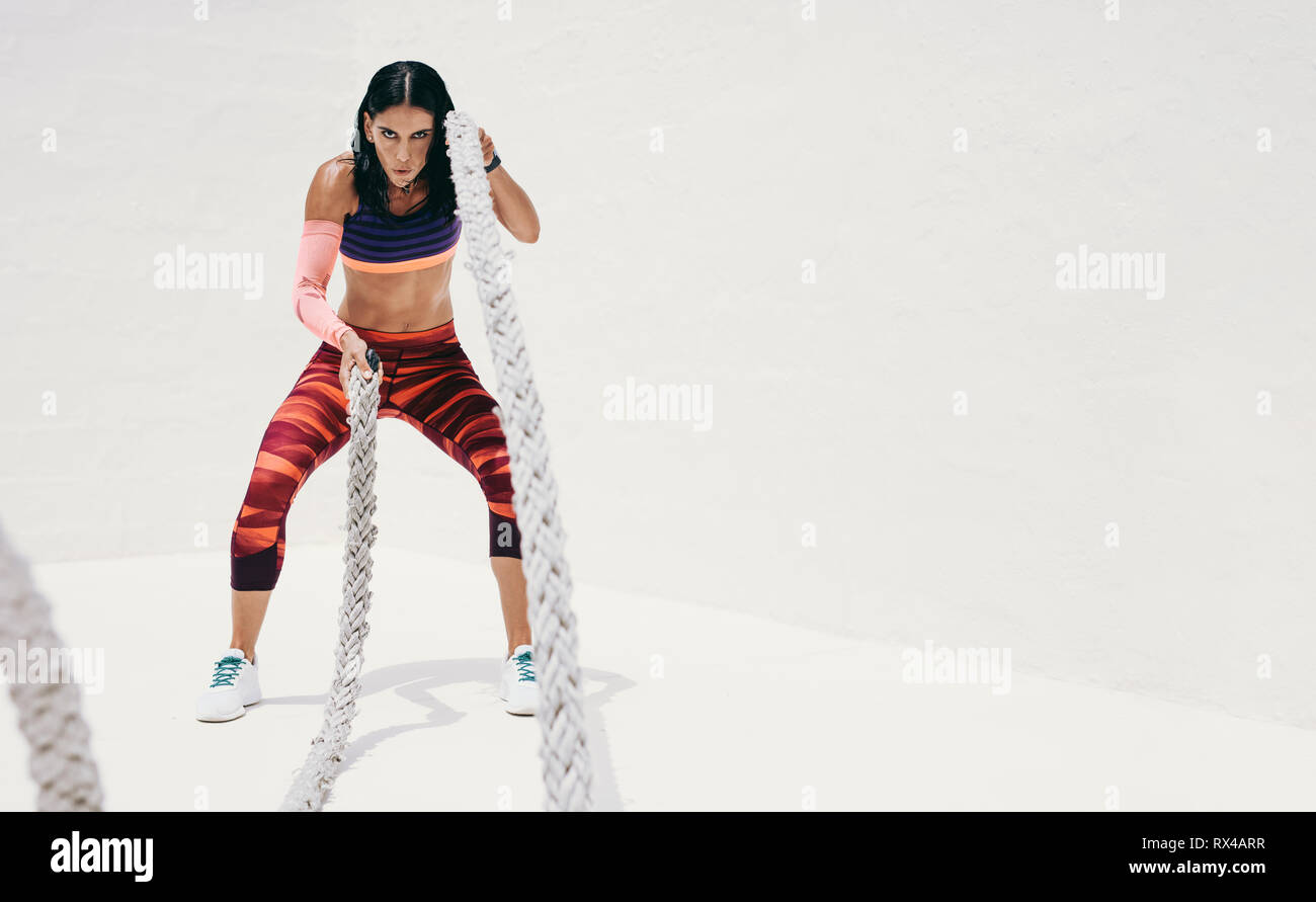 Fitness woman doing strength training using battle ropes. Athletic woman doing workout with battle ropes. Stock Photo