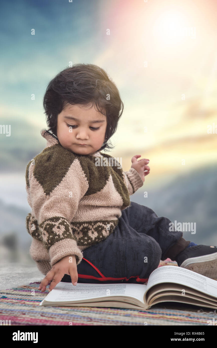 Portrait of little toddler girl sitting on the floor and looking book ...