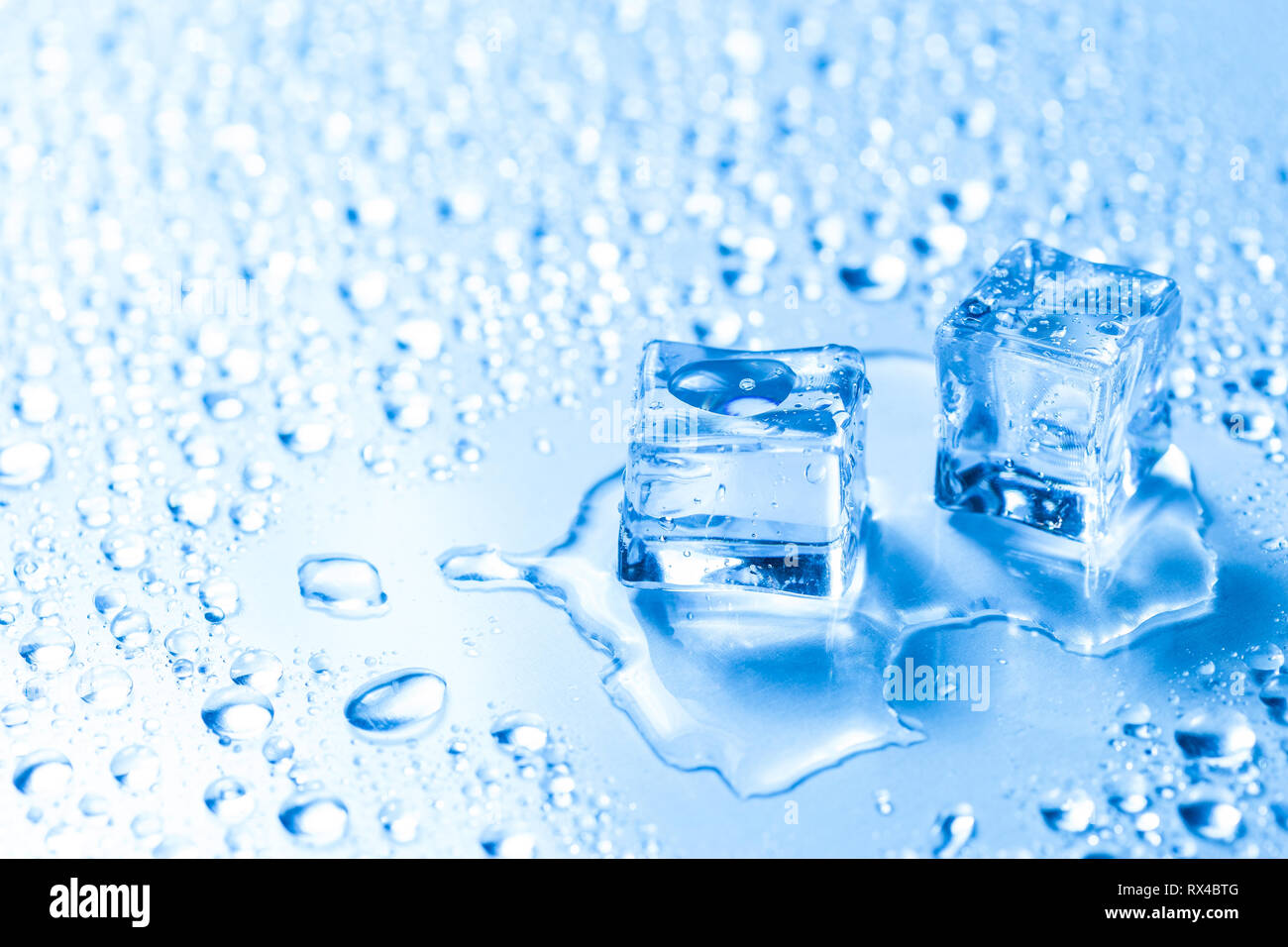 Two melted ice cubes with water drops over glass table Stock Photo