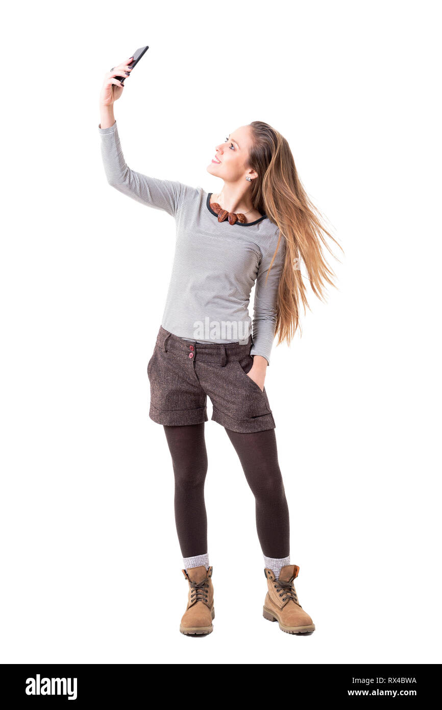 Happy excited young hipster girl taking selfie and tossing long