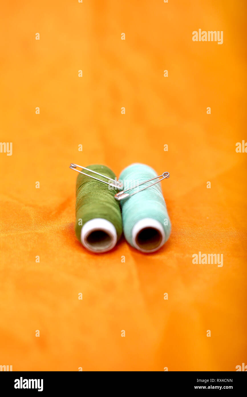 Picture of safety pin and sewing thread. Isolated on the yellow background. Stock Photo