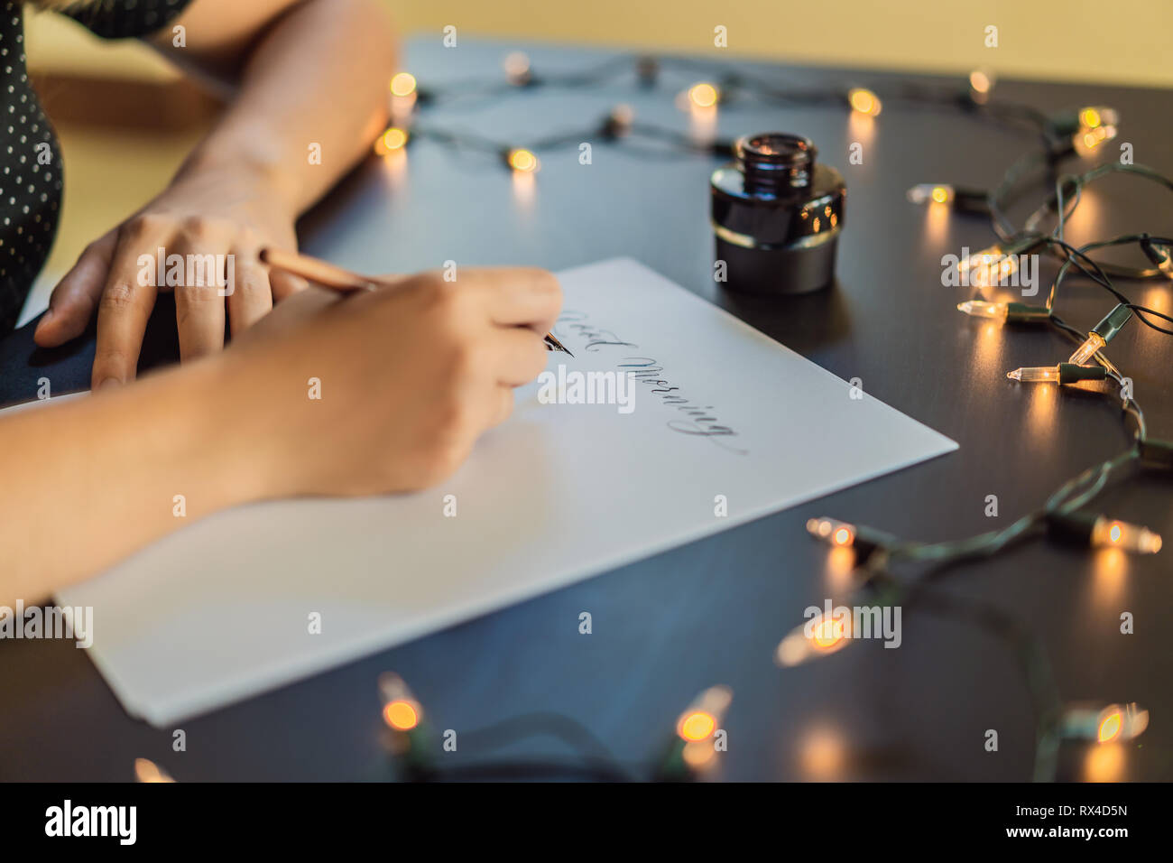 Calligrapher hands writes phrase on white paper. Phrase - Good morning ...