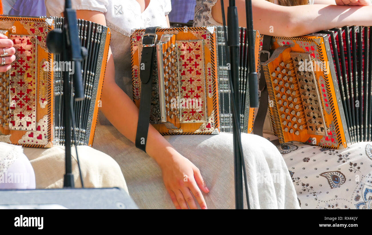 Girls in dress holding their accordions. They are sitting on the the chair with the microphone in front of them Stock Photo