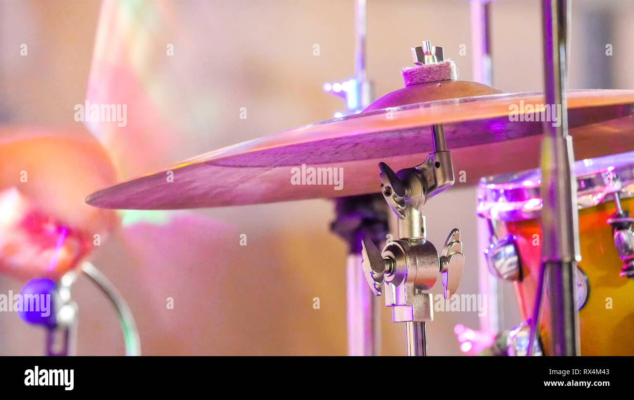The cymbals on the drums played on the stage. The drummer is banging on