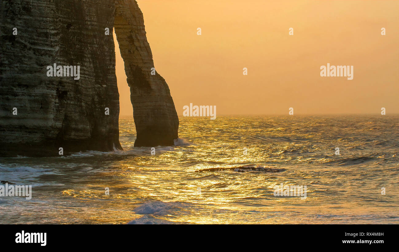 Late afternoon view of the beach and cliff in Etretat. Splashing of ...