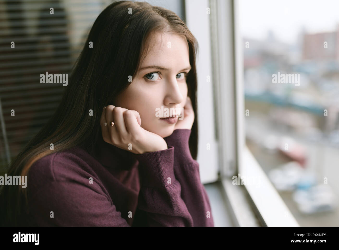 Sad woman looking through the window Stock Alamy