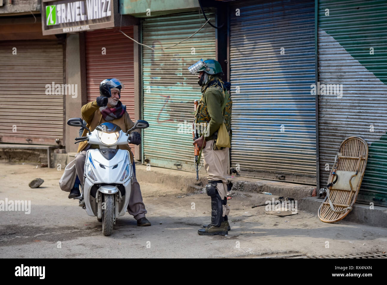 An Indian trooper seen stopping a man on a scooter during restrictions in down town area of Srinagar. Authorities imposed restrictions in parts of Srinagar Kashmir to prevent protest called by Joint Resistance Leadership (JRL) against the detention of Jammu and Kashmir Liberation front chairman Yasin Malik and the arrest of Jamaat-e-Islamia cadres. Stock Photo