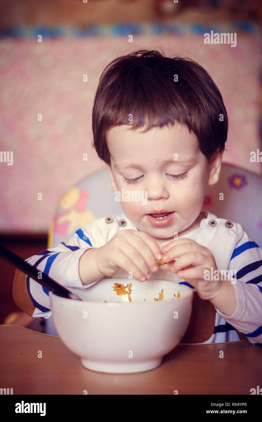 The boy eats himself from the plate. An independent child. The child