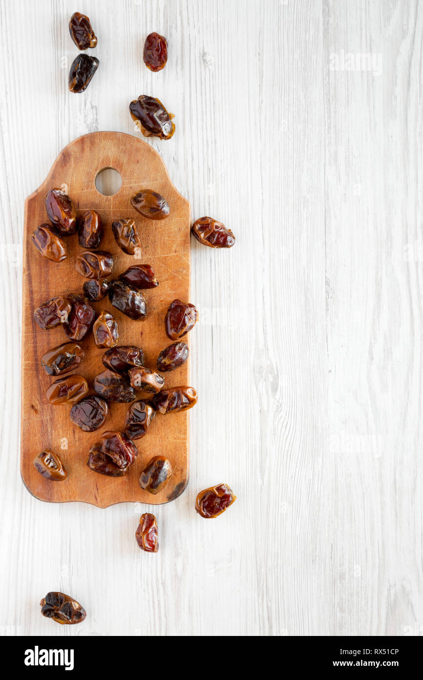 Dried dates on rustic wooden board on white wooden surface, top view ...