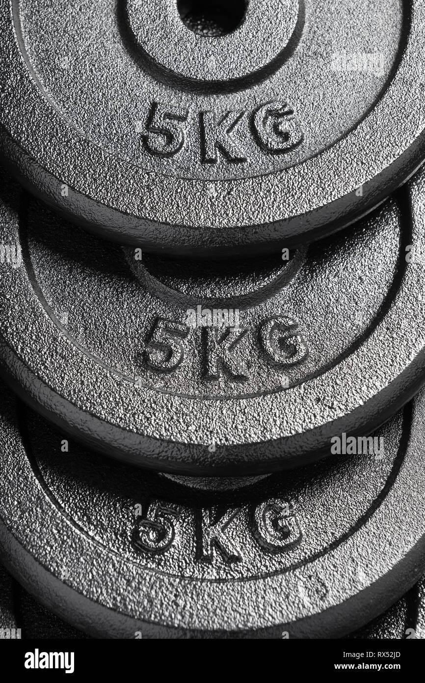 Stack of 5kg barbell / dumbbell weight plates inside a weightlifting gym Stock Photo