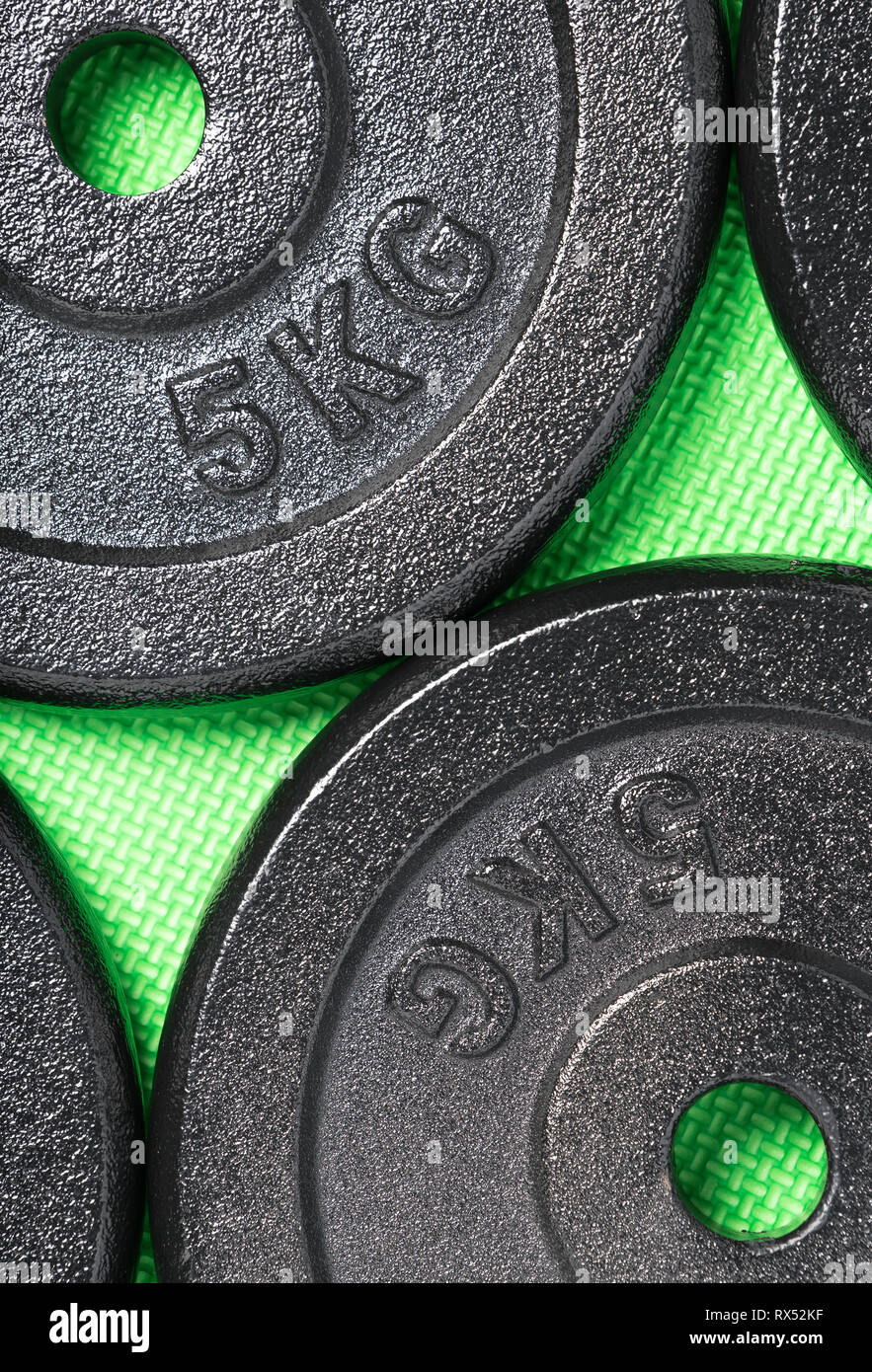 Exercise weight plates on a green floor inside a weight training gym Stock Photo