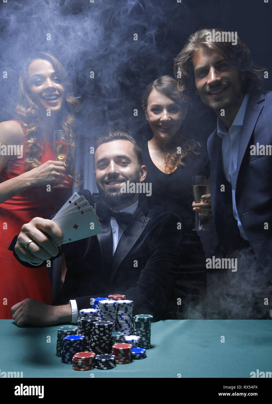 portrait of group of people with drinks playing poker in casino Stock Photo