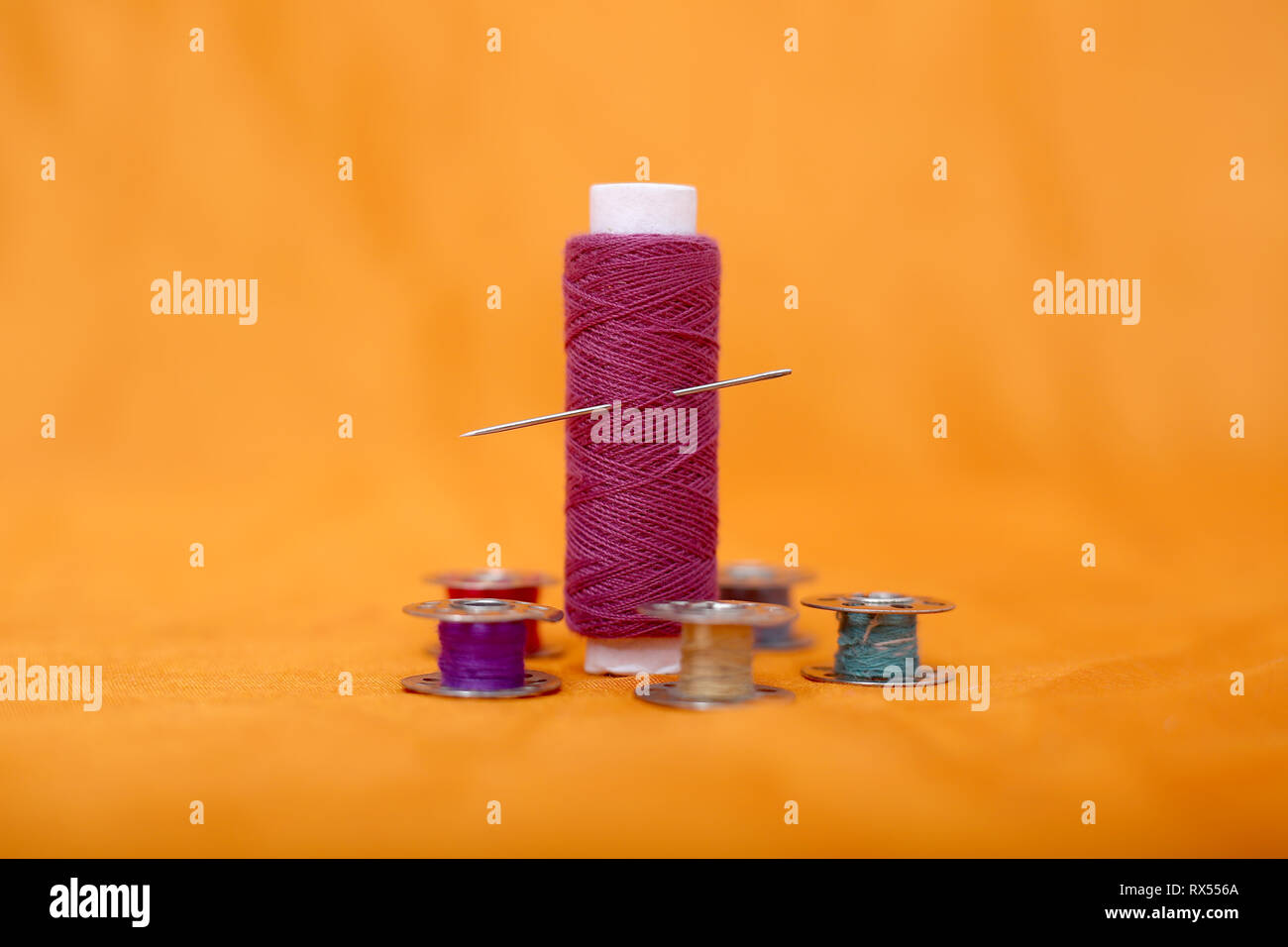 Photo of bobbin, thread and needle . Isolated on the yellow background ...