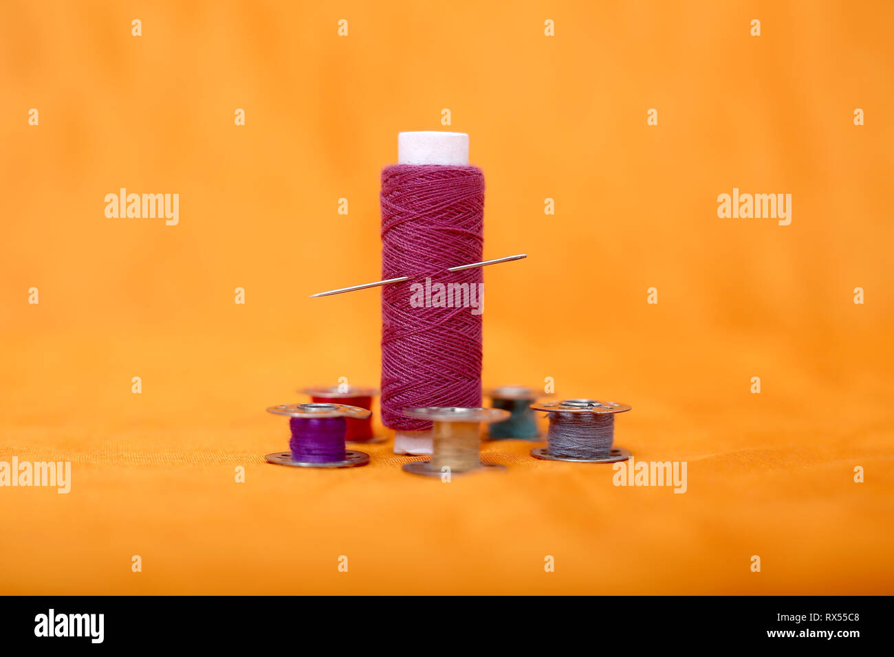 Portrait of one pink thread and bobbins. Isolated on the yellow background. Stock Photo