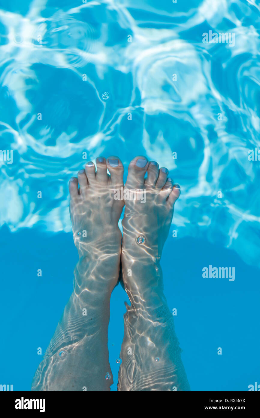 Closeup of beautiful female legs in water of a pool. Legs in the pool