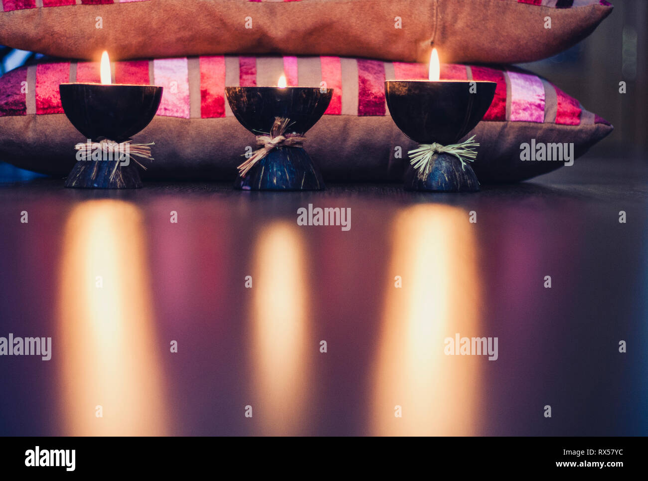 Burning spa aroma candles in coconut shell and burgundy pillows with