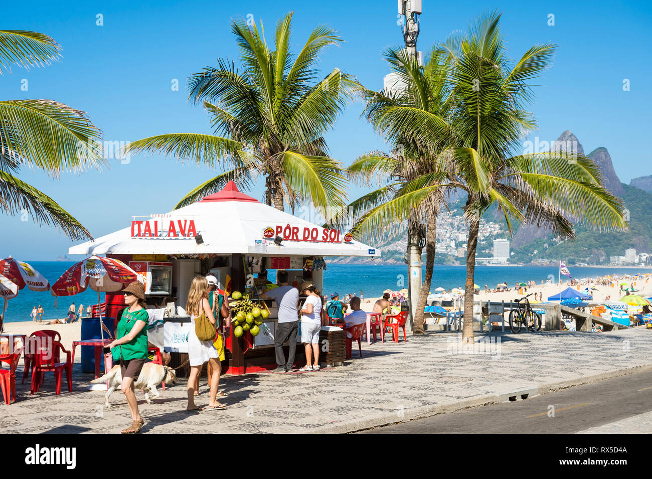 RIO DE JANEIRO - FEBRUARY 19, 2017: Customers stand at a kiosk selling drinks and coconuts at the Arpoador end of Ipanema Beach. Stock Photo