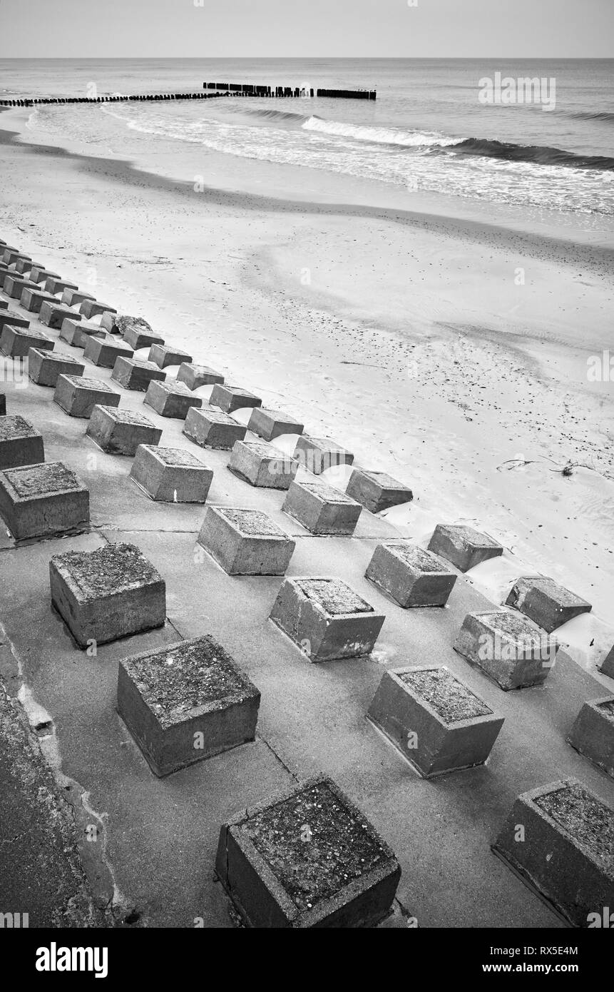 Black and white picture of concrete breakwater on a beach. Stock Photo