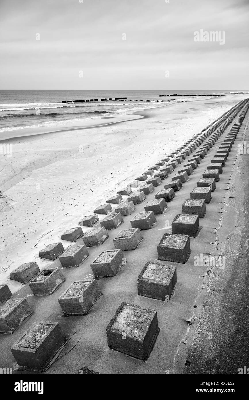 Black and white picture of concrete breakwater on a beach. Stock Photo
