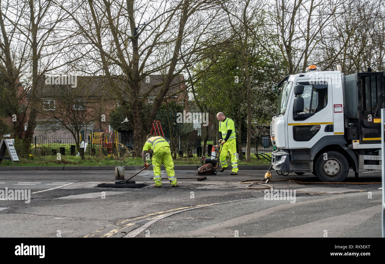 Workmen lay tarmac as the final step to completing some roadworks. Stock Photo