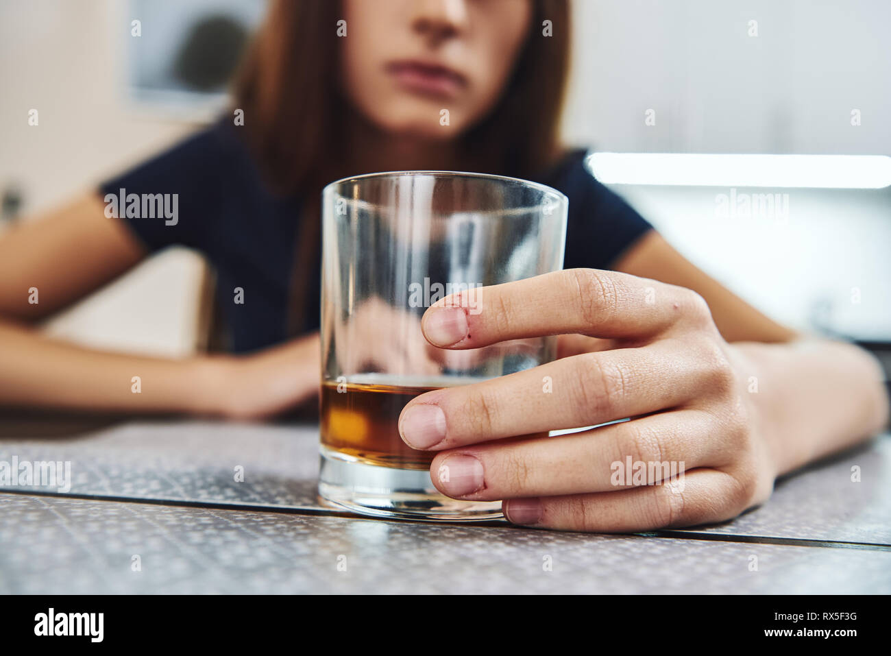 A glass of whiskey standing on the table with female hand on it. Female alcoholism concept. Protest in the treatment of alcohol addiction. Selective f Stock Photo