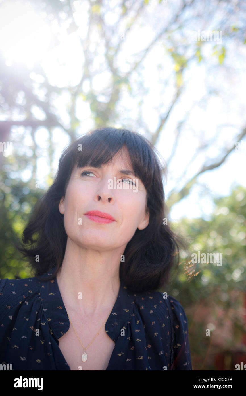 Close Up Of Beautiful French Woman Thinking To Herself With A Sideways Glance And A Smile With Light Up Trees And Garden In Background Stock Photo Alamy