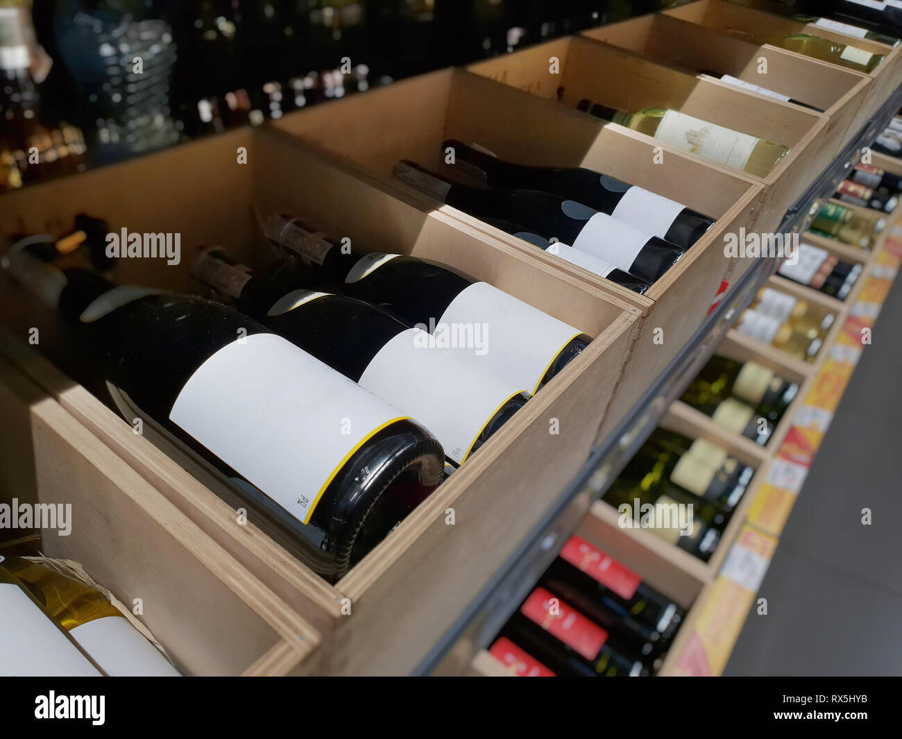 Wine bottles in a wooden crate. The labels of the closest bottles are empty. Stock Photo