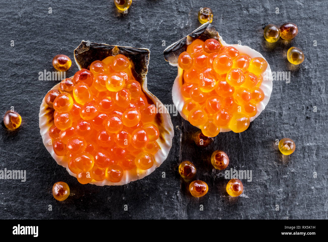 Caviar Shells Red caviar in the sea shells on gray graphite background. Macro picture ...