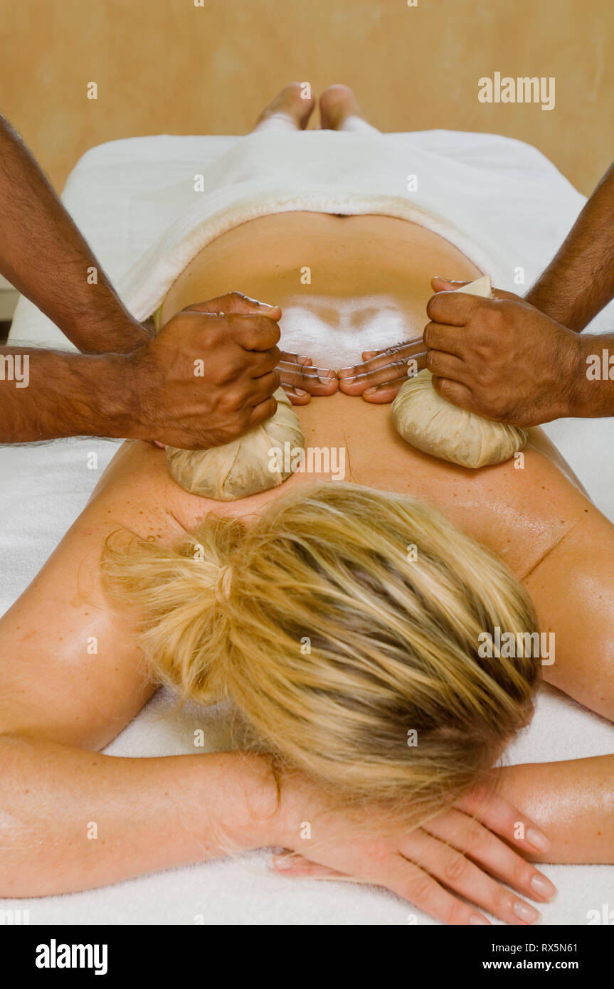 Woman being massaged with herbal compresses Stock Photo