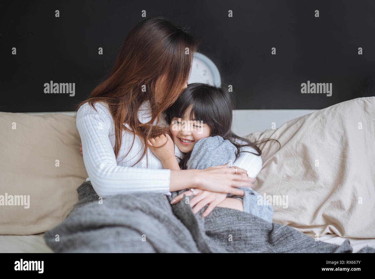 Happy mom and her daughter girl playing and hugging in bedroom Stock Photo
