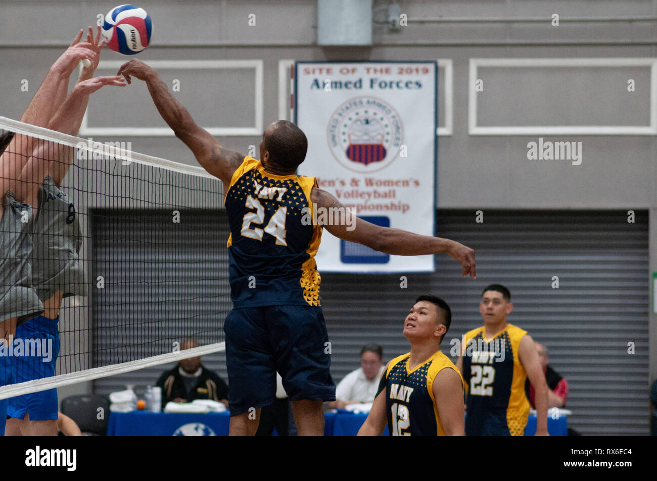 Fort Bragg, North Carolina, USA. 8th Mar, 2019. March 8, 2019 - Fort Bragg, N.C., USA - All-Navy Men's Volleyball Petty Officer 1st Class Sheldon Lucius (24) tips the ball over two defenders during the final match between the U.S. Air Force and U.S. Navy at the 2019 Armed Forces Men's Volleyball Championship at Ritz-Epps Gym on Fort Bragg. Air Force defeated Navy, 3-2, winning gold in the three-day round-robin tournament. The Armed Forces Men's and Women's Volleyball Championships are held annually. Credit: Timothy L. Hale/ZUMA Wire/Alamy Live News Stock Photo