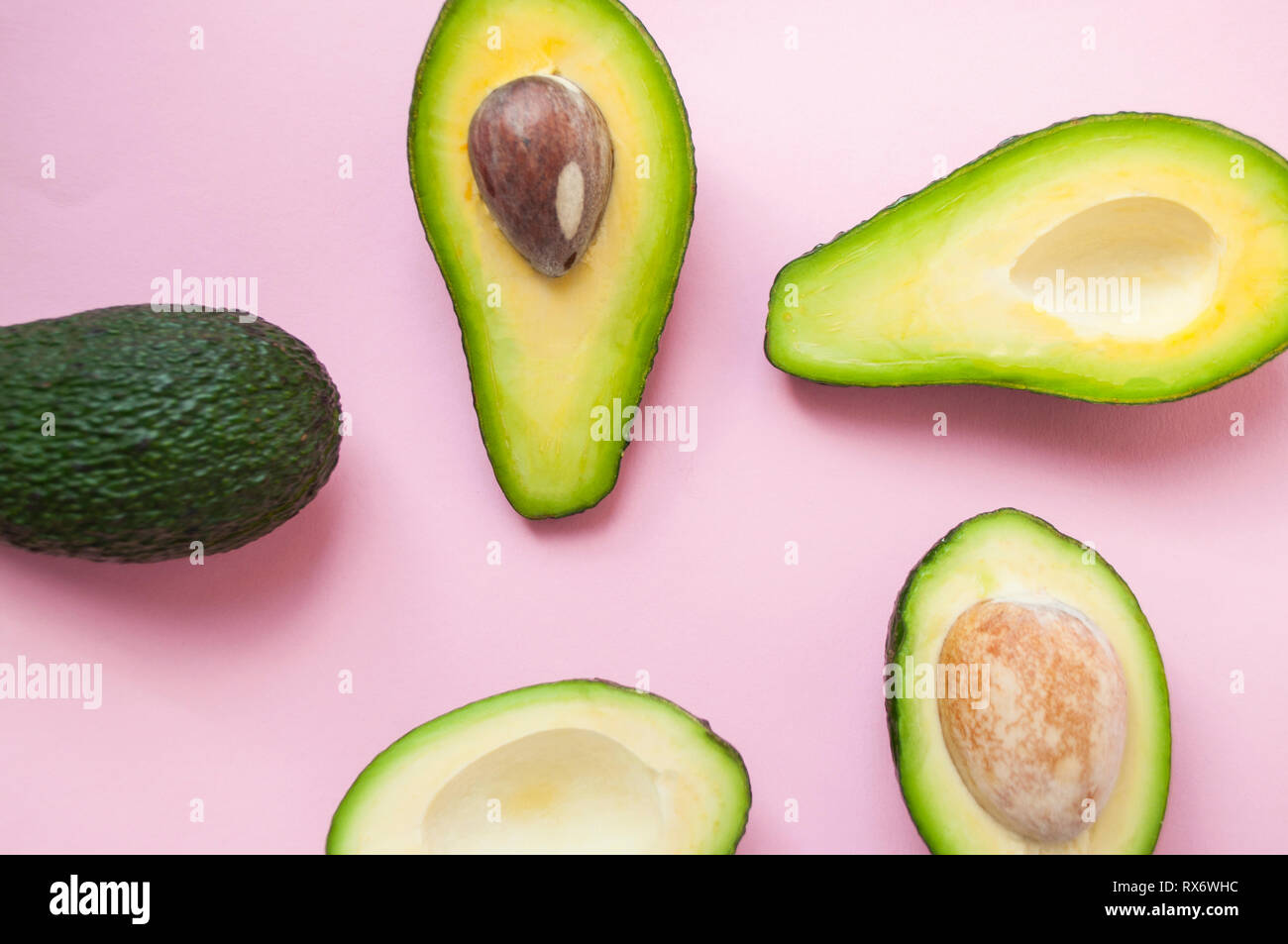 Ripe organic avocados with seed, avocado half and whole fruit on pink ...