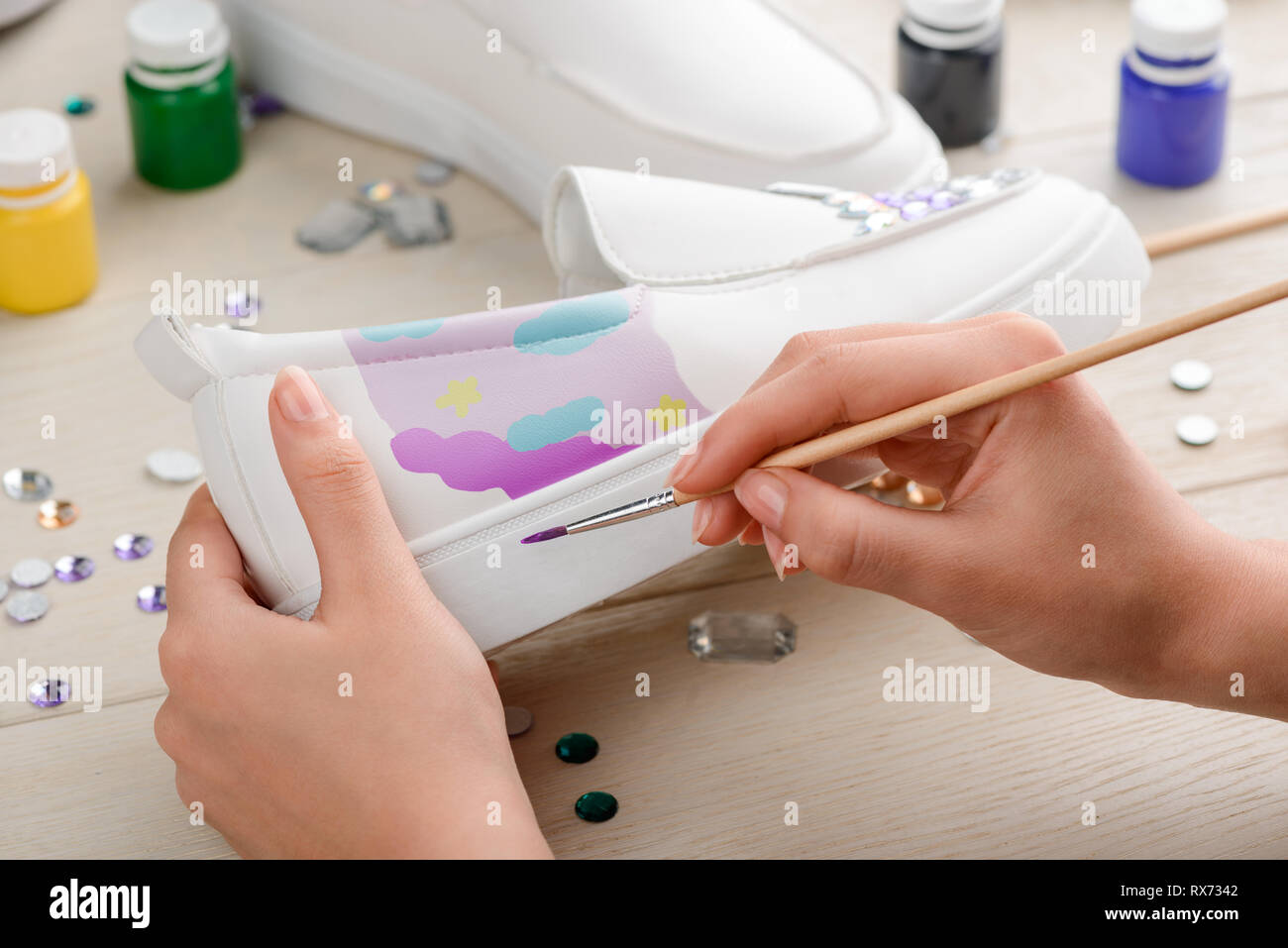 Artist painting slip-ons with brush Stock Photo