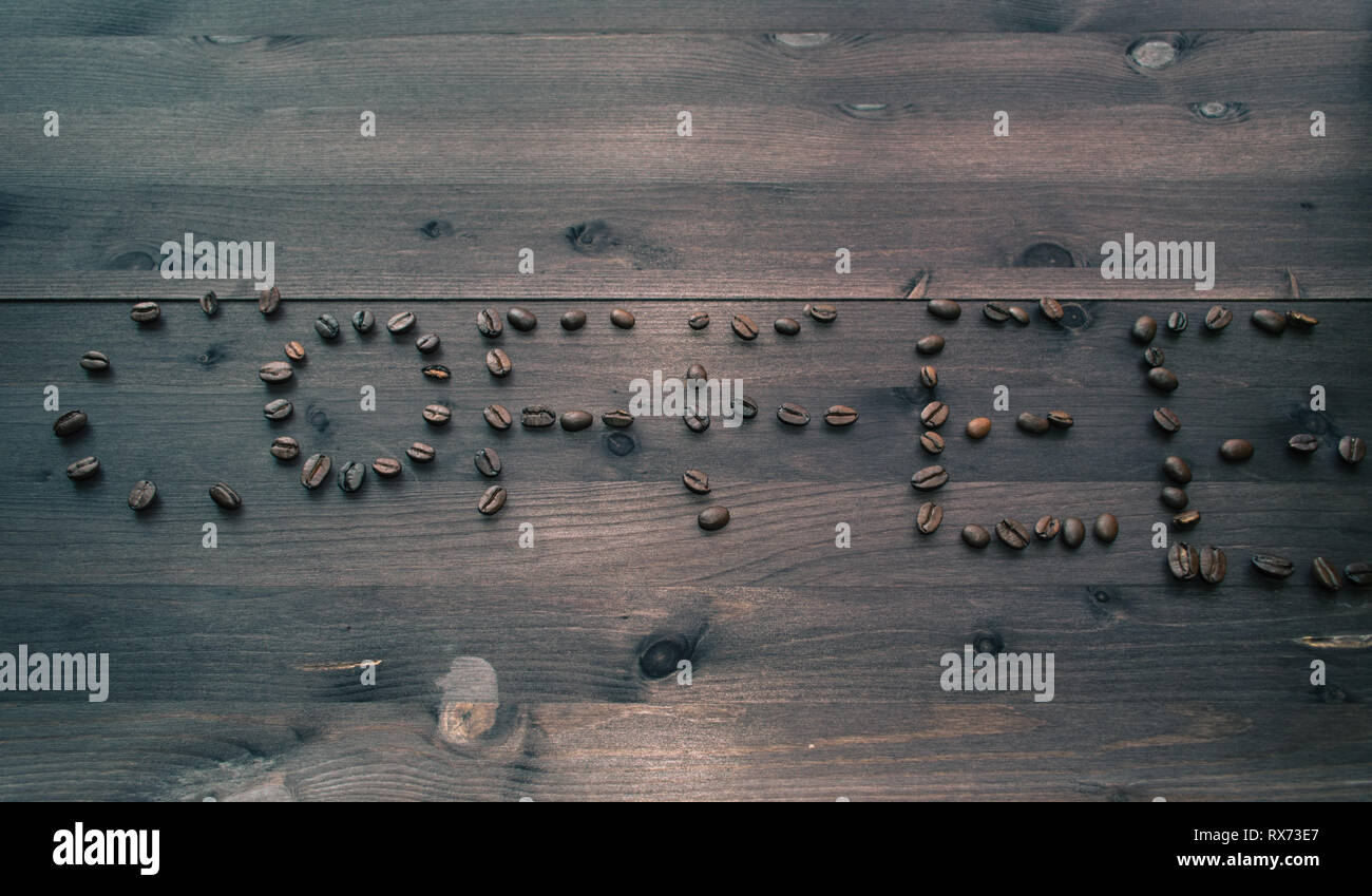 top view on coffee text made of coffee beans on dark wooden background Stock Photo