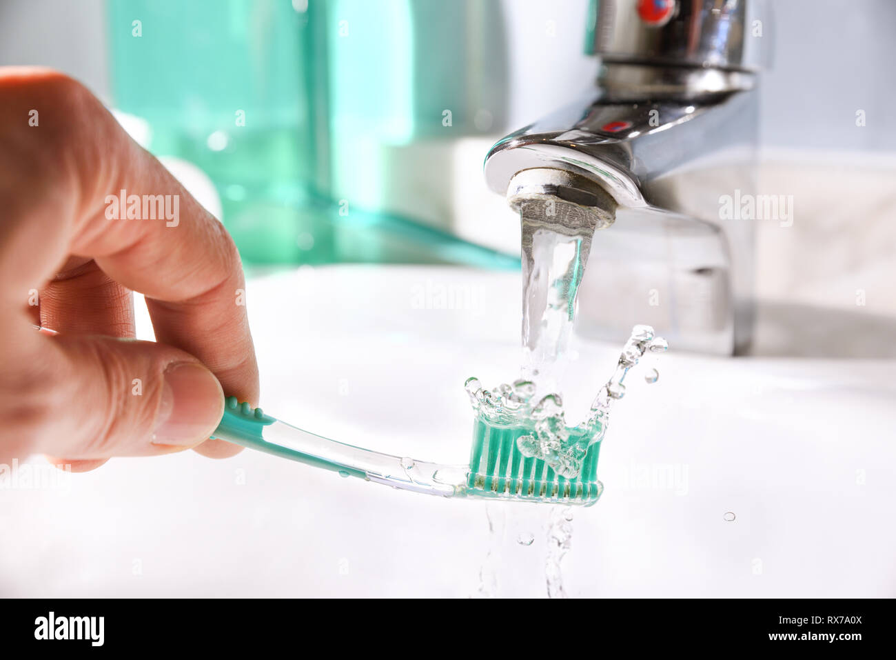 Daily cleaning of the toothbrush after use in the bathroom sink. Horizontal composition. Front view. Stock Photo