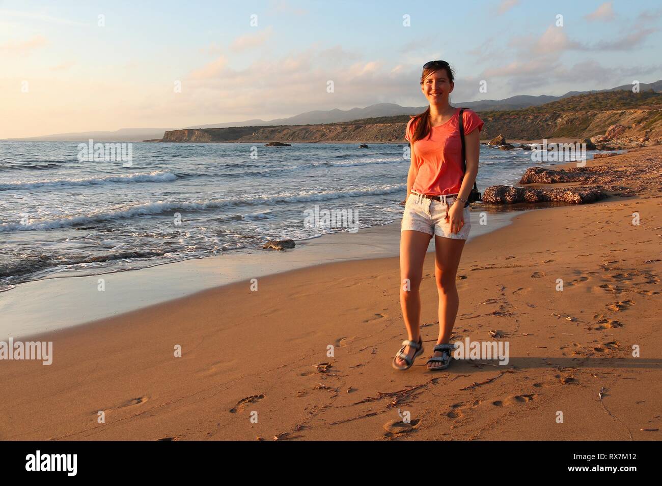 Female tourist enjoys beach walk in sunset light near Paphos, Cyprus. Stock Photo