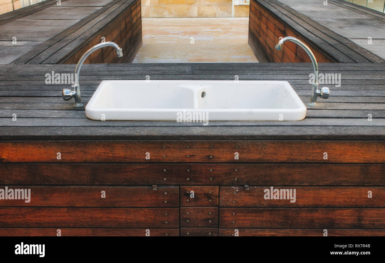 Porcelain hand wash basin set in a wooden platform outside in a modern stylish garden Stock Photo