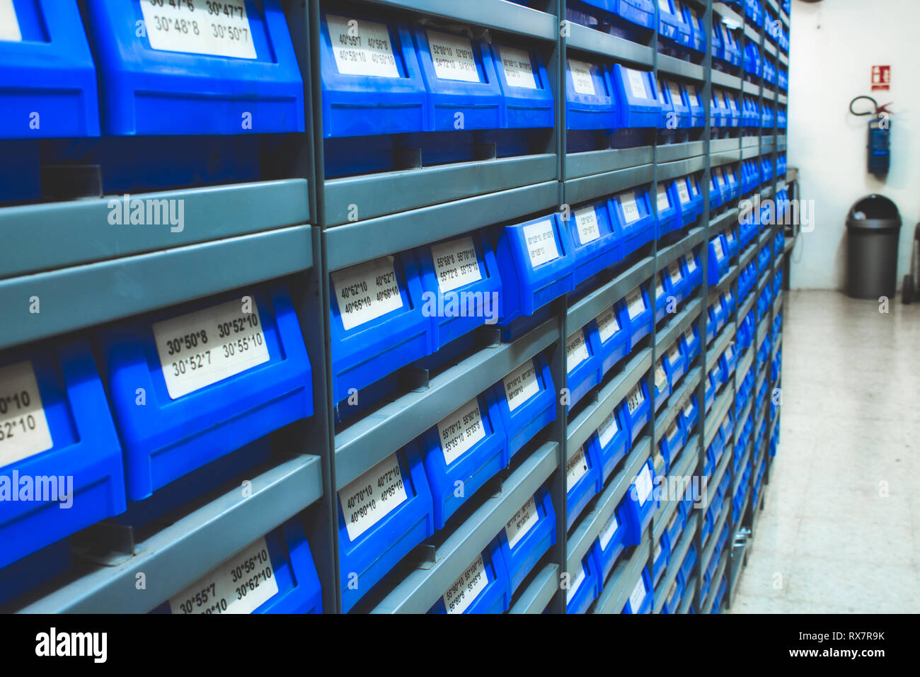 Blue plastic draws of stock / parts in rows of shelves in a warehouse Stock Photo