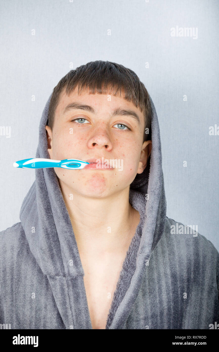 Teenage caucasian boy cleaning his teeth in the morning wearing a