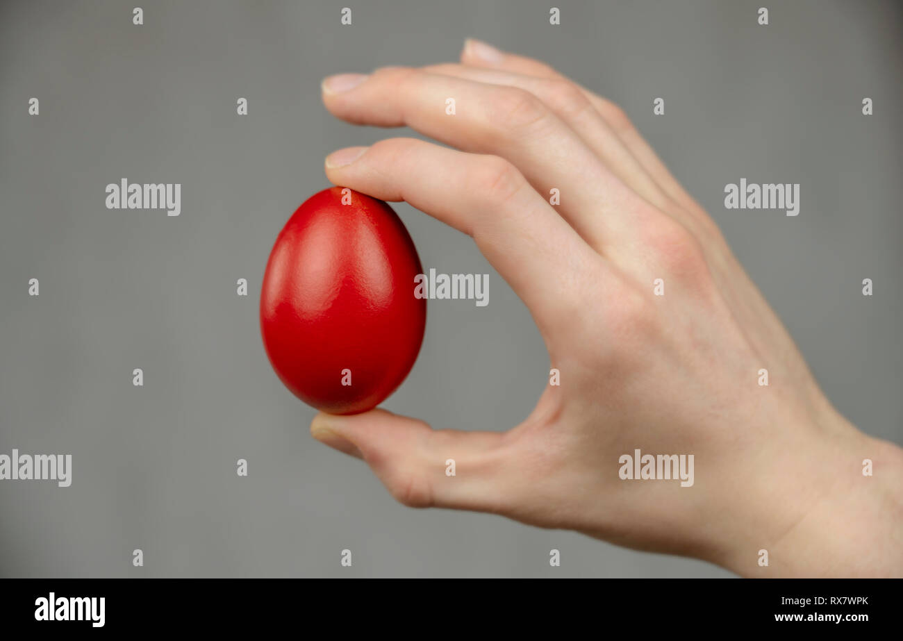 Easter red egg sandwiched between fingers on white abstract background Stock Photo Alamy