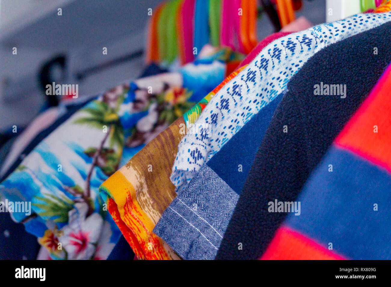 Closeup of child boy's summer clothes hanging in a closet, showing shirts and sweaters. Stock Photo