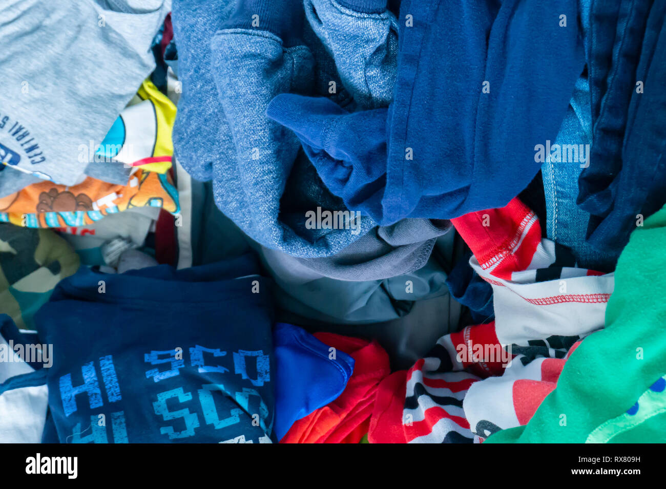 Little boy's clothing pile representing clothing donation, kid's drawer, cleaning up, pile of clothes, disorganization and cleaning up. Stock Photo