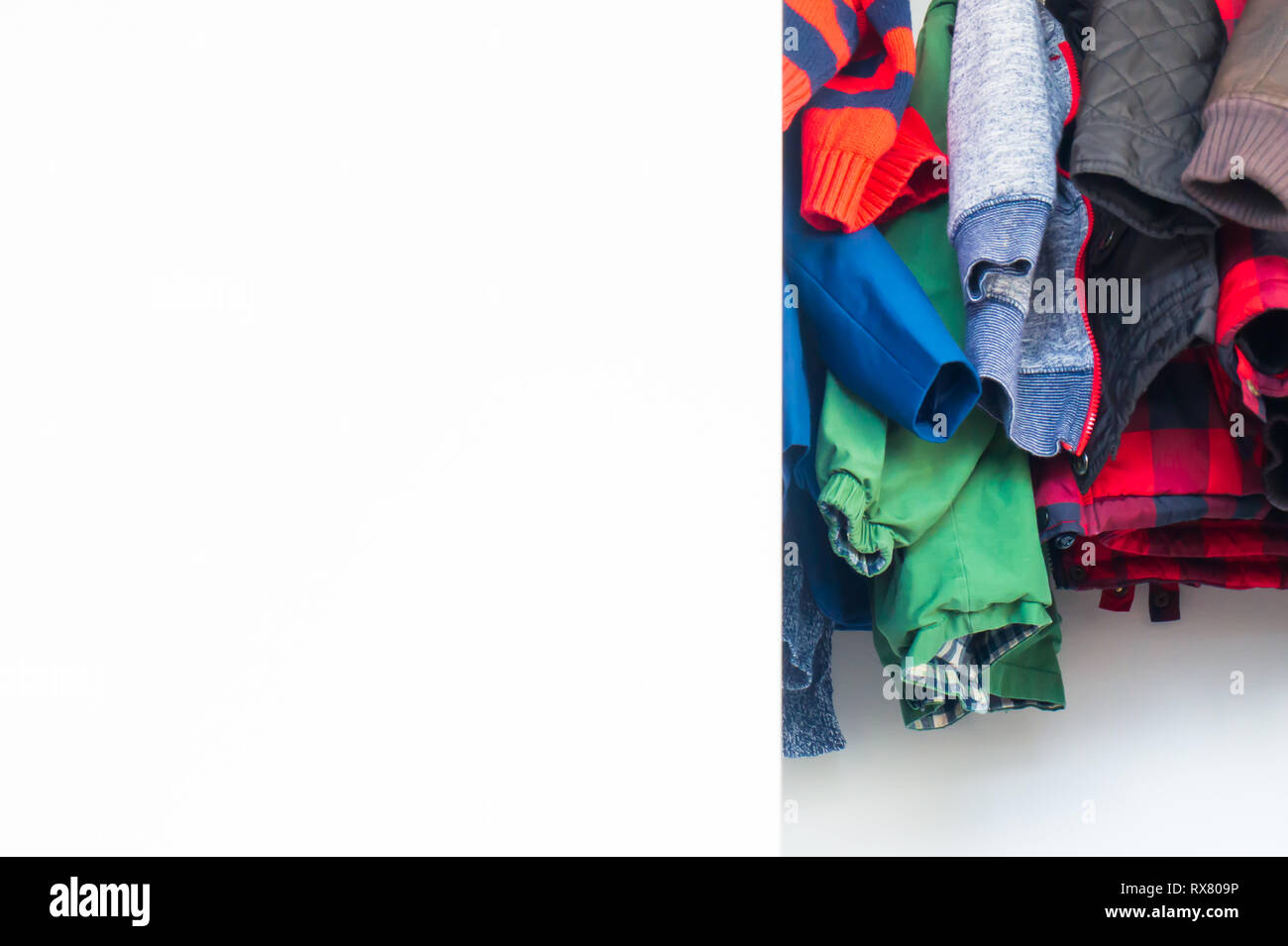 Bottom of boys jackets and winter clothes hanging in a real closet with lots of white space for copy, room for text. Stock Photo