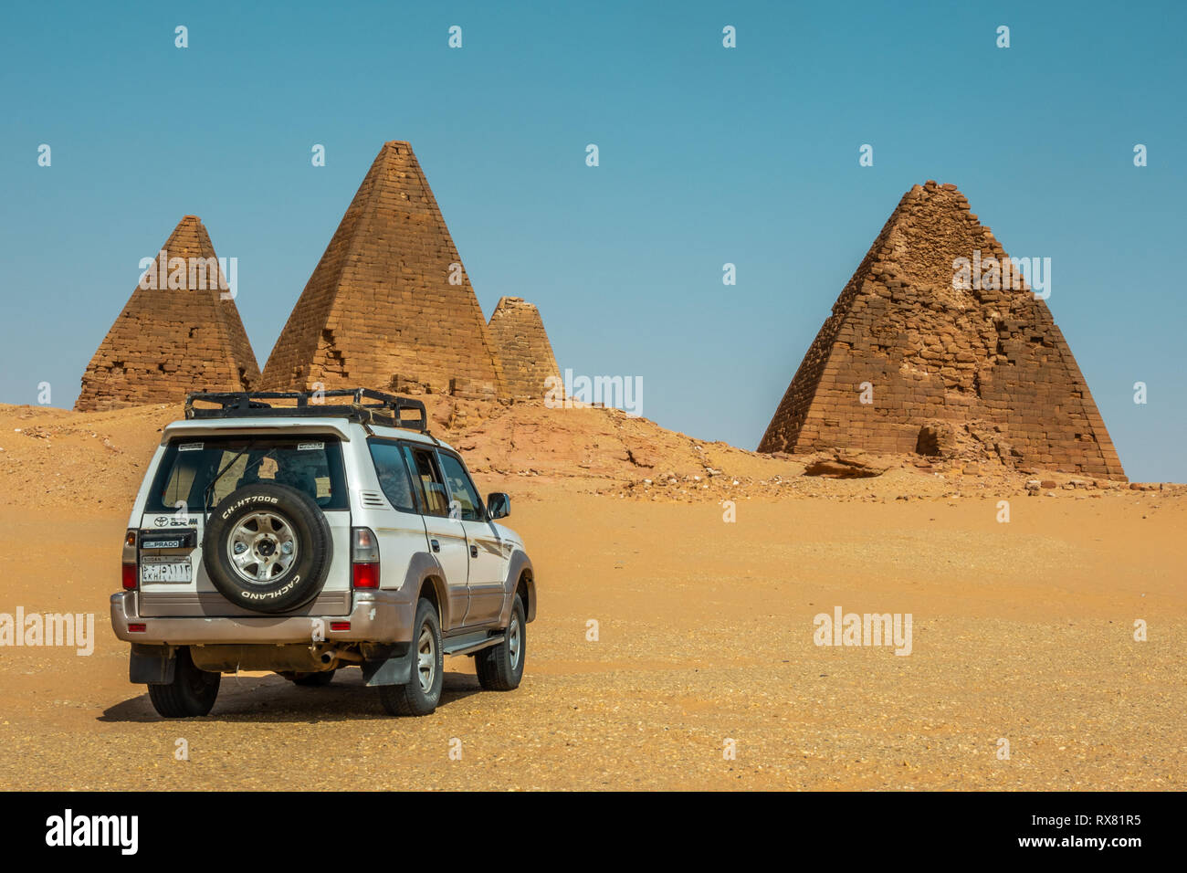 Nuri, Sudan, February 9., 2019: Off-road vehicle in the desert sand in front of three pyramids in Sudan Stock Photo