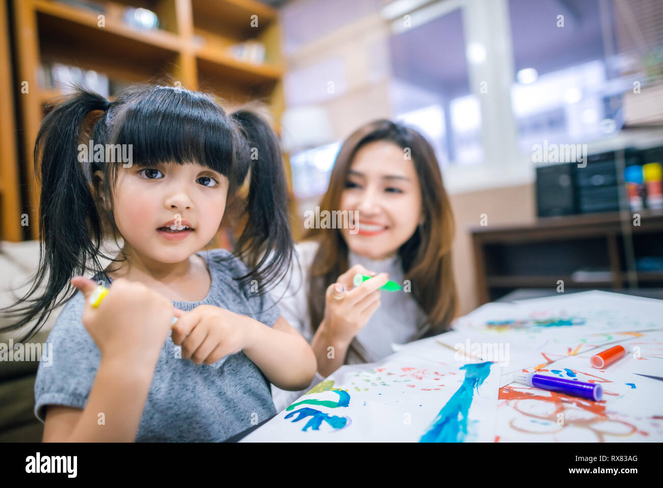 Cute little girl painting a picture with mother at home Stock Photo