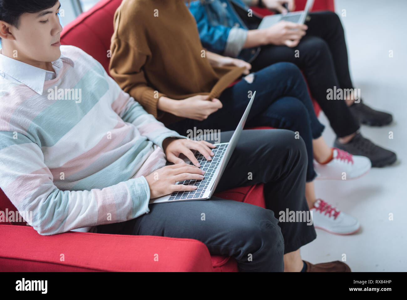 Group of friends sitting on sofa using laptop and smartphone technology ...