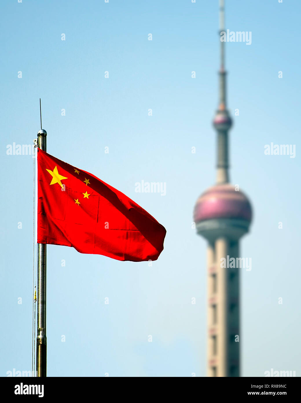 The Chinese flag blows in the wind. Behind it the Oriental Pearl Tower a landmark structure of Shanghai. Pudong, Shanhai, China. Stock Photo
