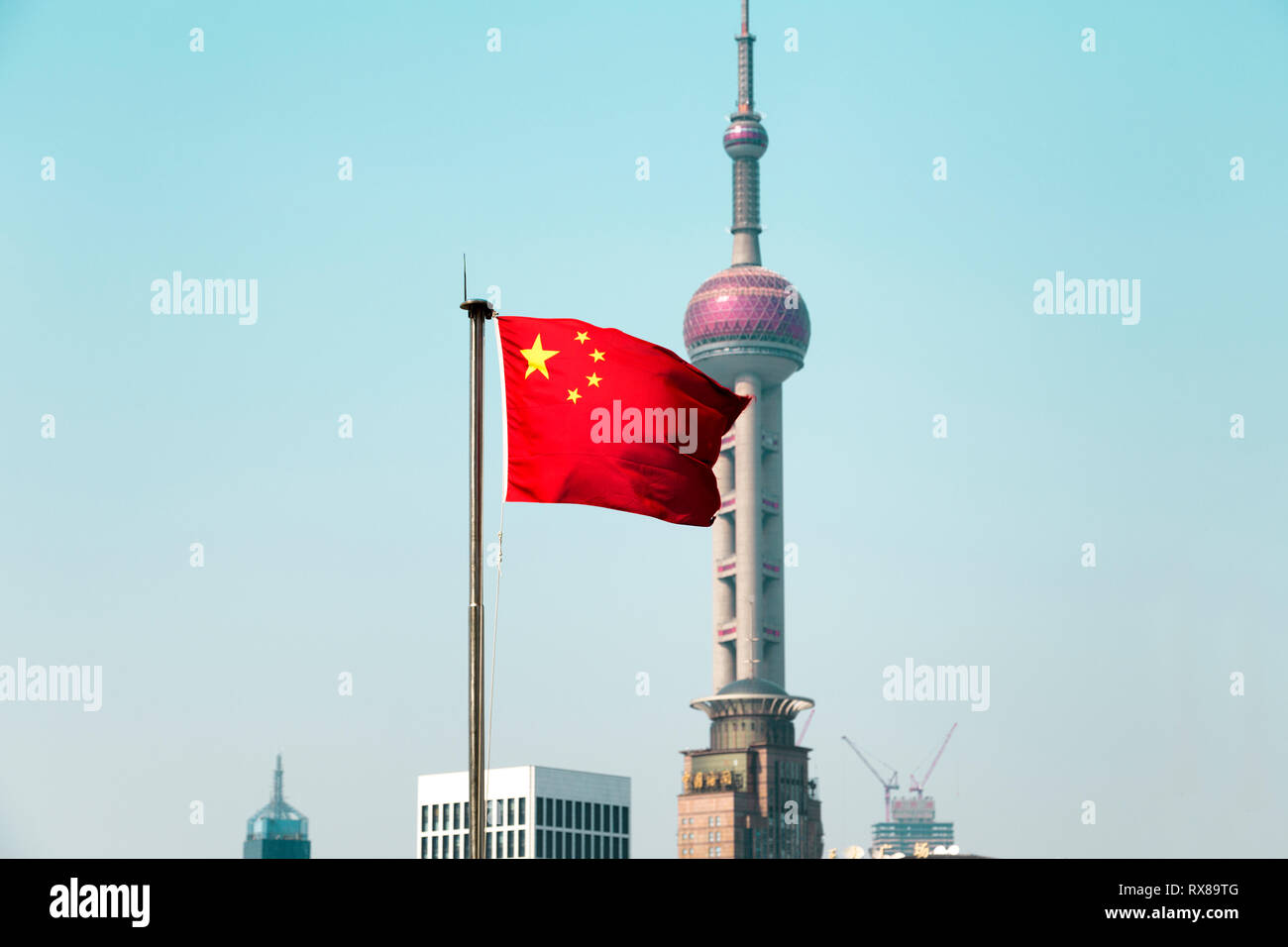 The Chinese flag blows in the wind. Behind it the Oriental Pearl Tower a landmark structure of Shanghai. Pudong, Shanhai, China. Stock Photo